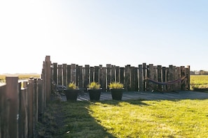 Een houten hek met bloempotten en een hangmat.