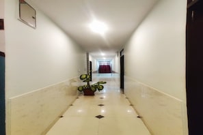 A corridor with a potted plant, a door at the end, and a red curtain. - Hotel Fountain Hills (Kukas)