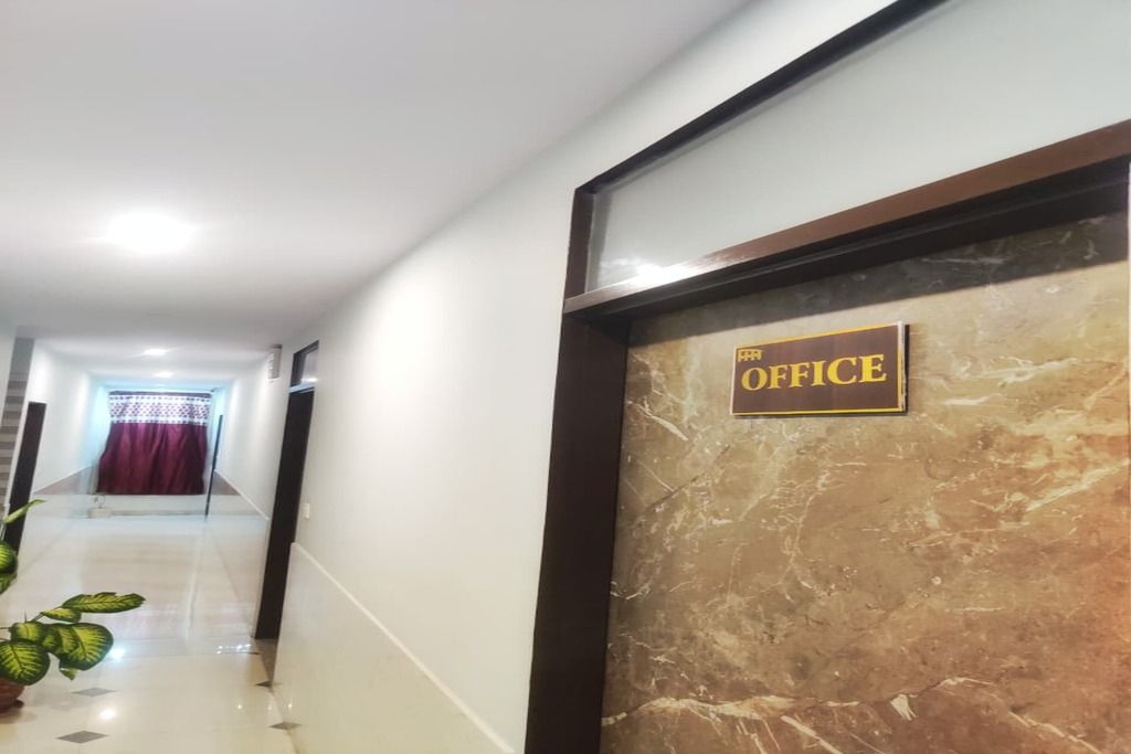 Un couloir avec un mur de marbre et une pancarte sur laquelle on peut lire : « Le bureau ».