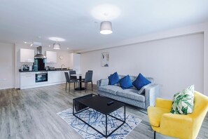 A modern living room with a grey sofa, blue cushions, a yellow armchair, and a black coffee table. - Bright and Modern 2BDR 2BA Relaxing City Stay (Manchester)