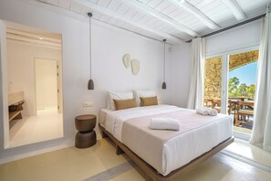 Ein modernes Schlafzimmer mit einem großen Bett, Nachttischen und Blick ins Freie.