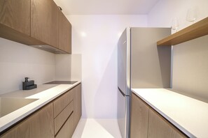 Eine moderne Küche mit Holzschränken, einem Edelstahlkühlschrank und einer weißen Arbeitsplatte.