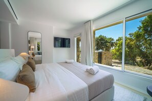 Un dormitorio moderno con una cama grande, un televisor y vistas al exterior.