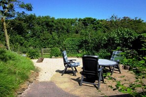 An outdoor seating area with two chairs and a table, surrounded by a gravel path and greenery. - Holiday apartment with 2 bedrooms (Callantsoog)