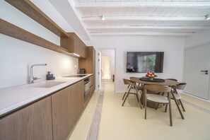 Eine moderne Küche mit Holzausbau, einer Edelstahlspüle und einem Essbereich mit rundem Tisch und Stühlen.