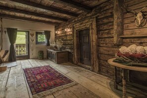 A rustic cabin interior with a wooden floor, a colorful rug, a door with heart-shaped decorations, and a deer skull mounted on the wall. - Hut in Taxenbach with swimming pool (Taxenbach)