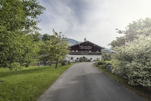 A building with a balcony, a paved driveway, and surrounding greenery. - Hut in Taxenbach with swimming pool (Taxenbach)