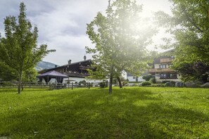 A grassy area with trees and a building with a balcony. - Hut in Taxenbach with swimming pool (Taxenbach)