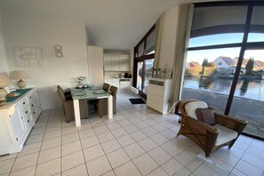 Un intérieur moderne comprenant un coin repas, une cuisine et une grande fenêtre donnant sur un plan d’eau.