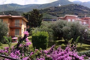 A residential area with houses, a well-maintained garden, and a mountainous backdrop. - Holiday apartment with 2 bedrooms (Malcesine)