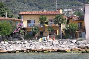 Un bâtiment situé sur la côte, doté d’un balcon et entouré de rochers et de palmiers.