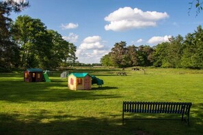 Un parc amb dues casetes de jocs, una taula de picnic i una banca.