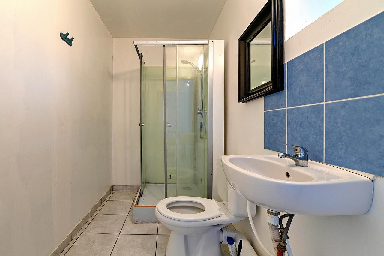 Een badkamer met een douchecabine van glas, een witte wastafel en een toilet.