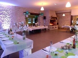A dining area with tables set for a meal, decorated with white flowers and green accents.