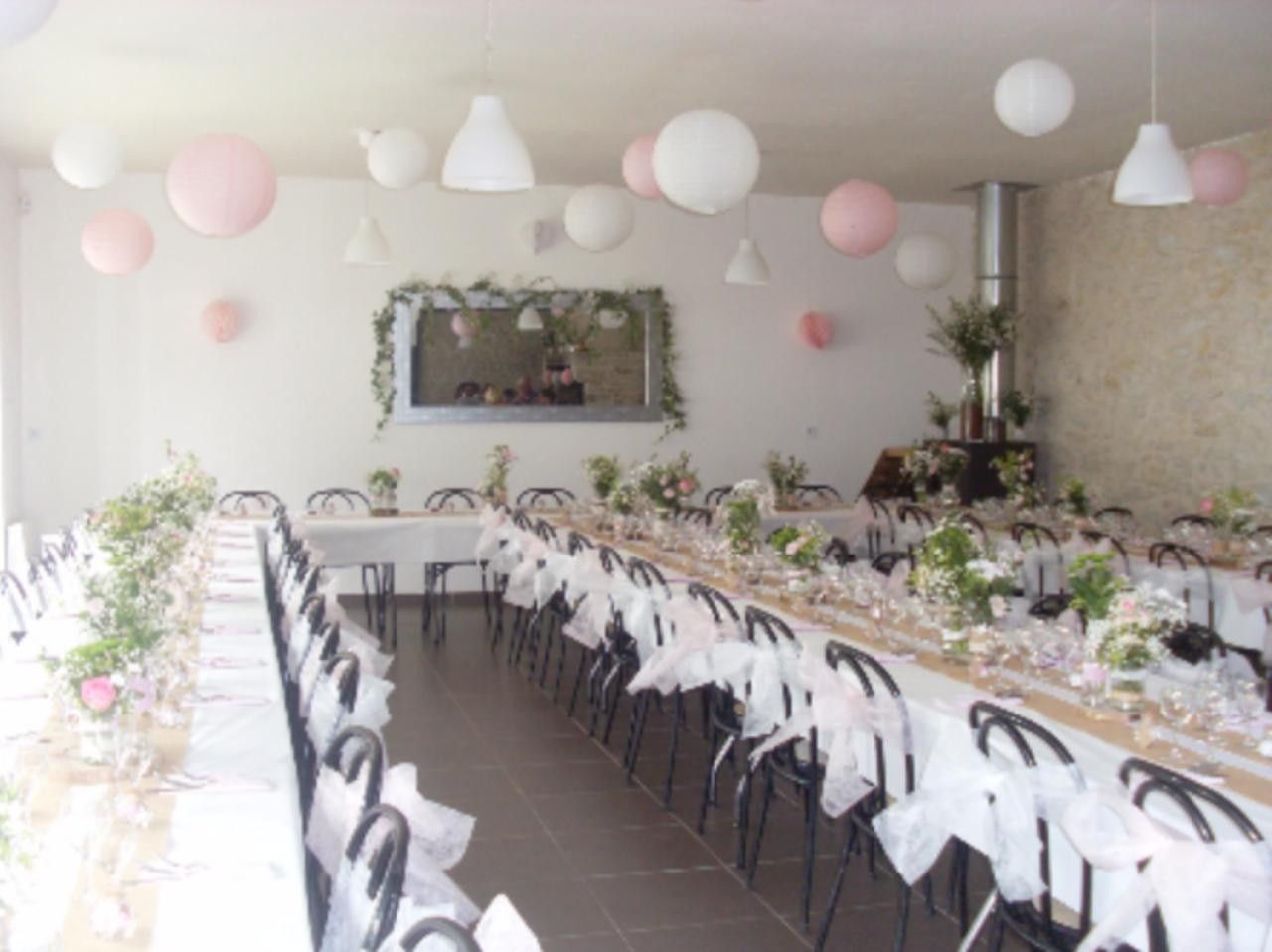 Een lange eettafel gedekt voor een formeel evenement, omringd door stoelen, met een decoratieve wand en hangende verlichting.