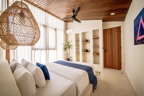 A bedroom with a bed, a ceiling fan, a wall-mounted air conditioner, and a large window with curtains. - Villa GIGI Balangan (Balangan)