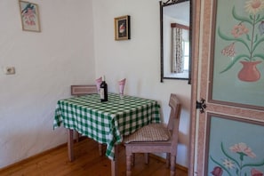 A dining area with a checkered tablecloth, a bottle of wine, and a chair. - Katharina's Alpine Hut (Mühlbach im Pinzgau)