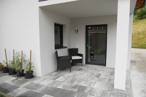 A covered patio area with a seating arrangement, a window, and a door. - Holiday apartment with 2 bedrooms (Eben im Pongau)