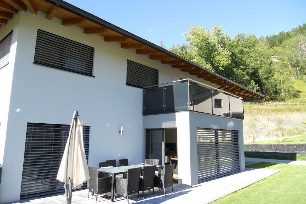 Ein modernes, zweistöckiges Gebäude mit Balkon, Außenbereich und Blick auf eine grüne Landschaft.
