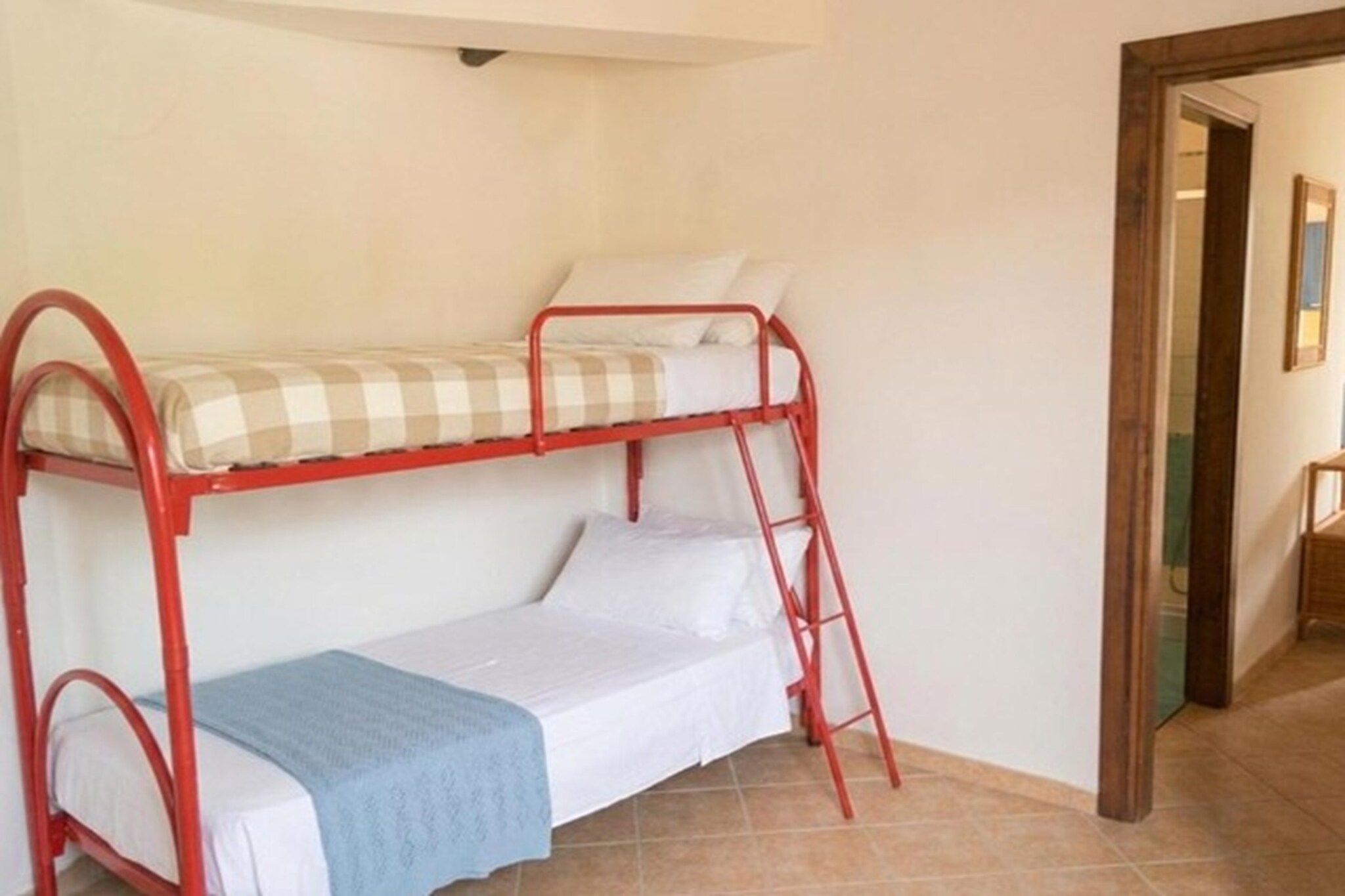 Un lit superposé avec une échelle, une couverture bleue et un oreiller à carreaux.