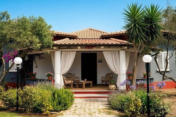 A covered outdoor seating area with a tiled roof, white curtains, and a small table with chairs. - Apartment with shared pool near the sea (Nicotera (VV))