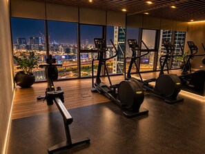 A gym with cardio equipment and a city view. - Burj viewsFrom bed paramount Luxe 3BR+ Pool infinity (Dubai)