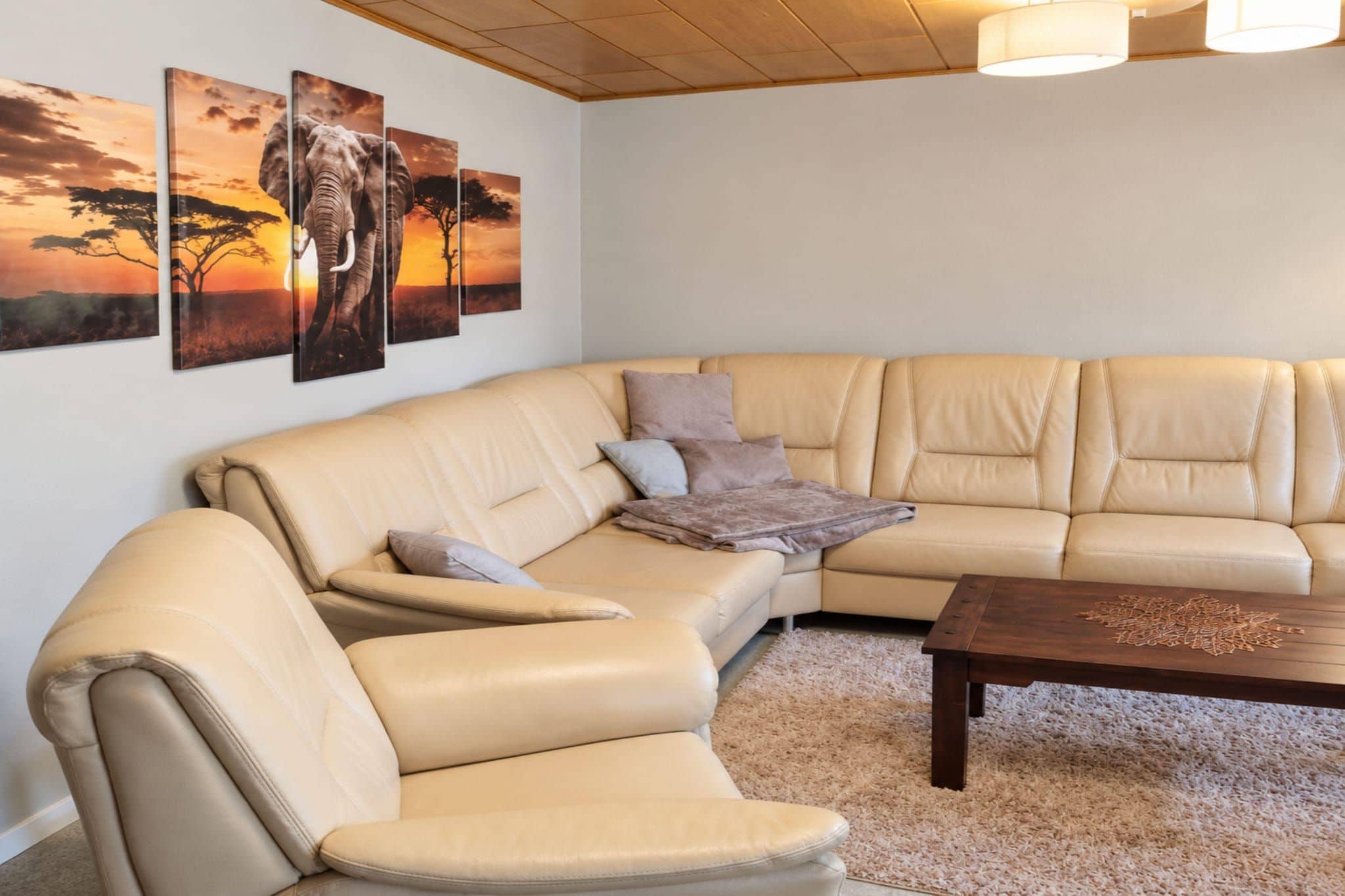A beige leather sectional sofa with a matching armchair and a wooden coffee table in a living room with a shaggy carpet.