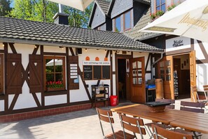 Ein traditionelles Gebäude im europäischen Stil mit einer Schautafel, die Öffnungszeiten anzeigt, Außenplätzen und einer einladenden Atmosphäre.