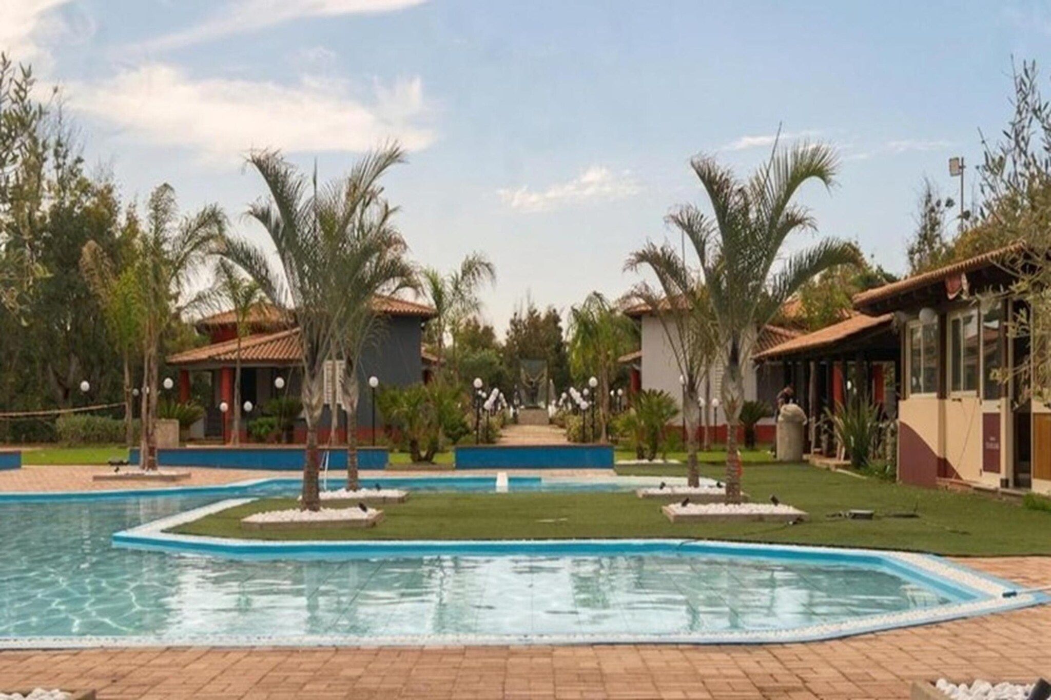 Une piscine entourée de palmiers et de bâtiments.