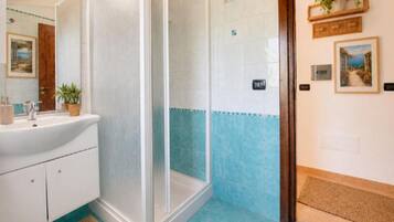 Ein Badezimmer mit Dusche, Waschbecken und Fliesenboden.