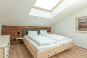 A bedroom with a skylight, wooden headboard, and a bed with white linens. - Apartment in Eben with swimming pool (Eben)