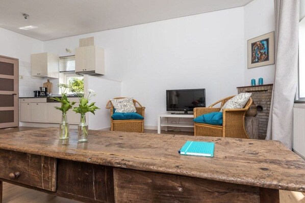 Une cuisine moderne avec des meubles blancs, une table à manger avec des chaises et un téléviseur.