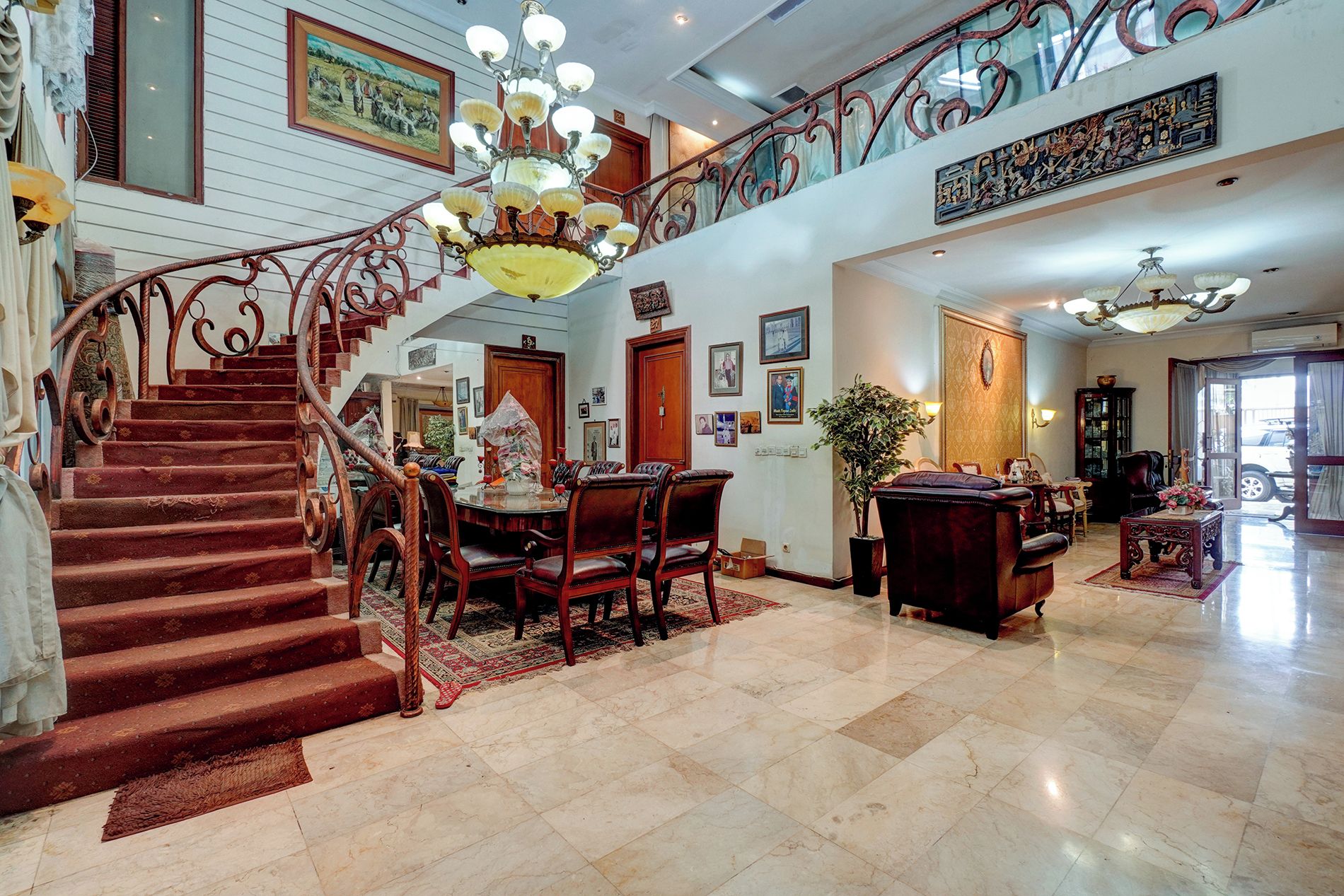 Una imponente escalera que conduce a un segundo piso, un comedor con mesa y sillas, y una sala de estar con sofá y mesa de centro.