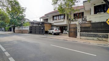Una calle residencial con casas, un camino de entrada con portón y un automóvil estacionado.