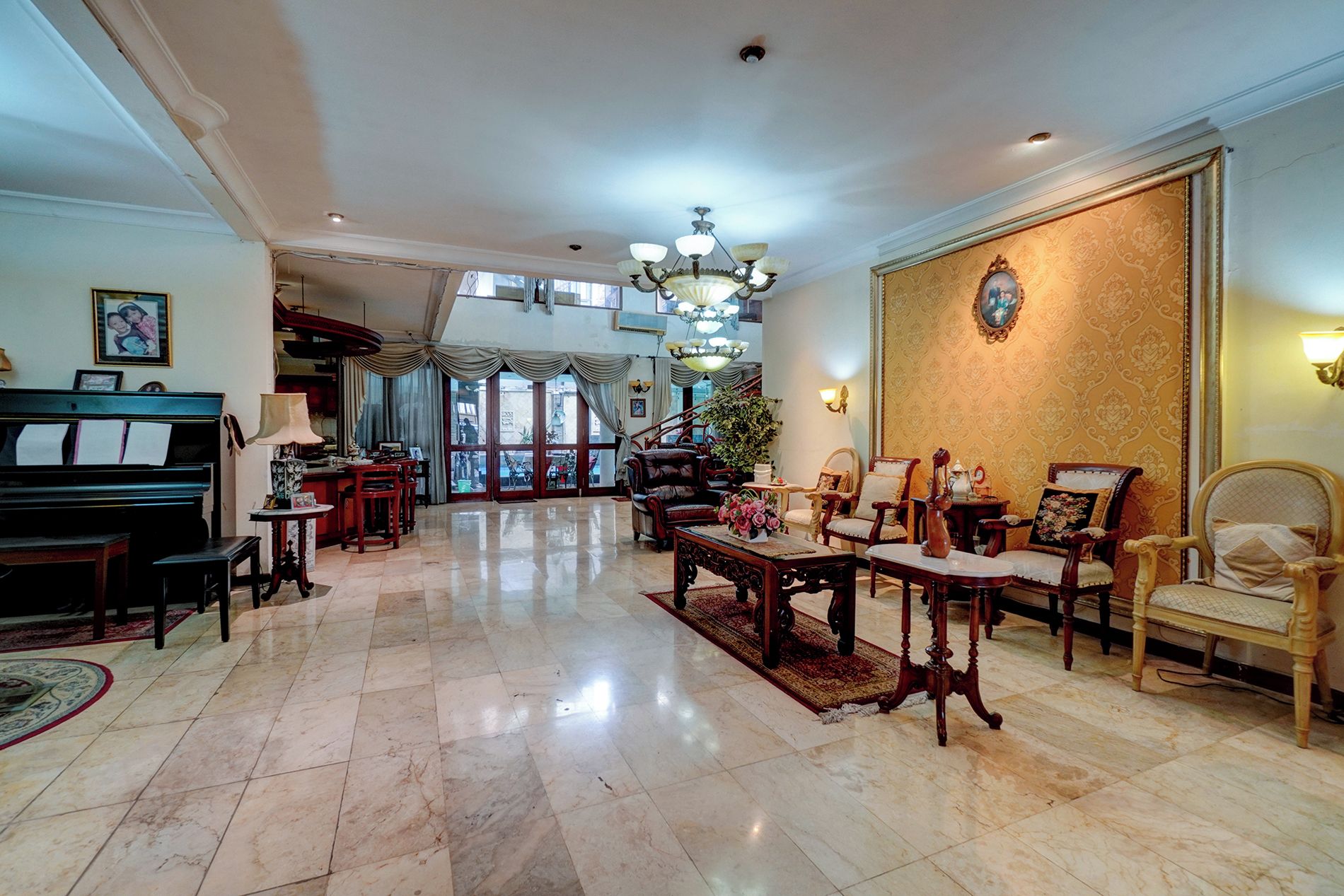 Un salón espacioso con un piano de cola, muebles elegantes y una araña.
