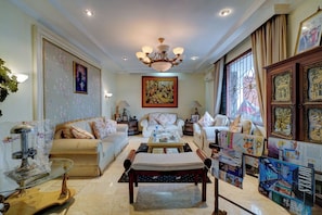 A spacious living room with a chandelier, sofas, a coffee table, and a fireplace. - Cassa Dharmawangsa By ARBA (Jakarta)