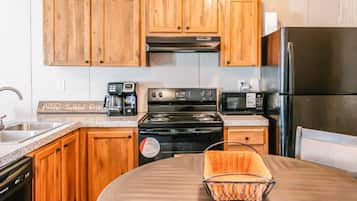 A kitchen with wooden cabinets, a black stove, a microwave, and a refrigerator.