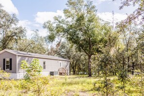 A single-story house with a front porch, surrounded by trees and grass.