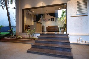 Un vestíbulo de hotel con una escalera que lleva a la entrada, un mostrador de recepción y un área de estar.