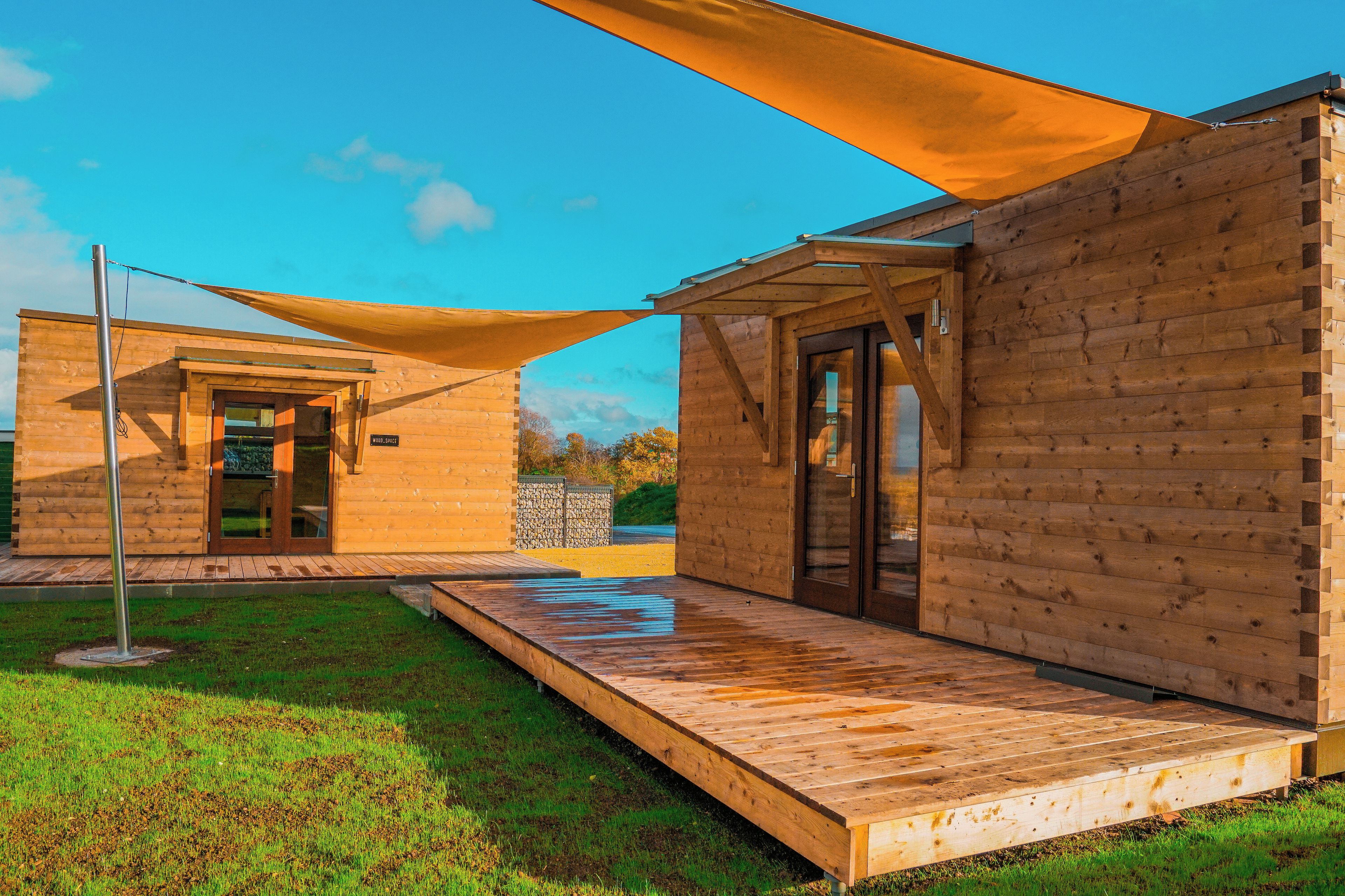 Une cabane en bois dotée d’un patio couvert et d’une porte donnant accès à un espace intérieur.