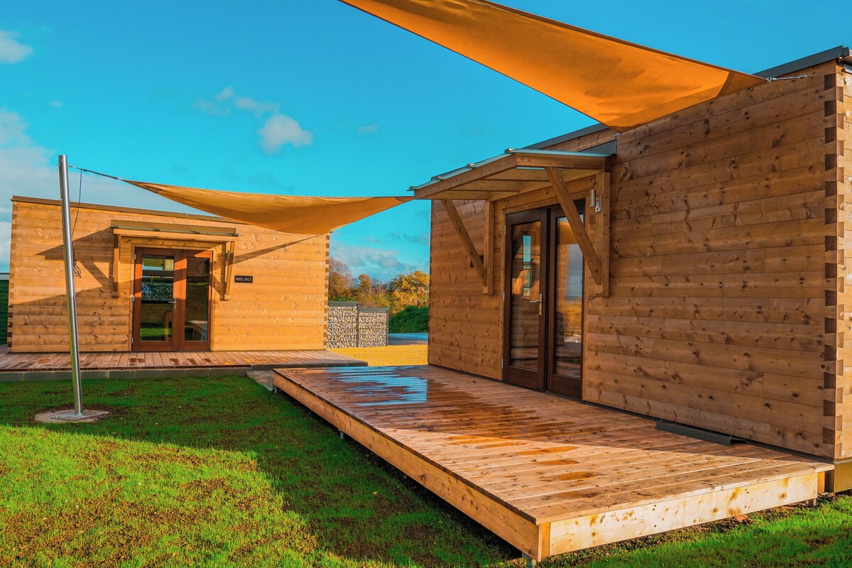 A wooden cabin with a covered patio and a door leading to an interior space.