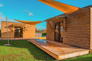 A wooden cabin with a covered patio and a door leading to an interior space. - Freizeitparadies Mohrenhof (Geslau)