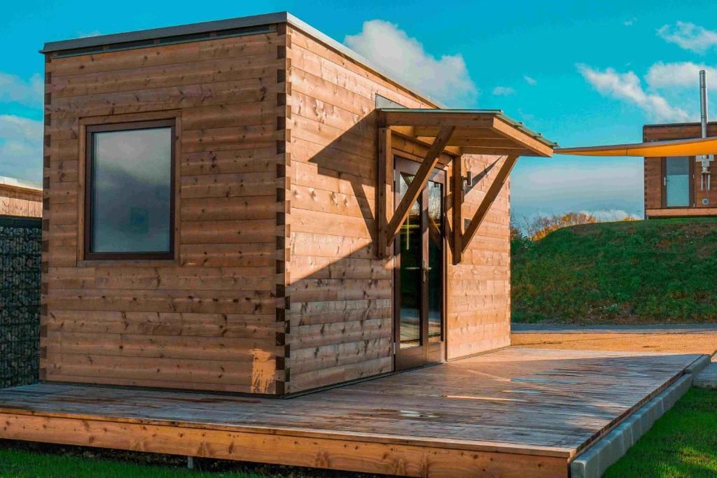 Uma cabana de madeira com porta de vidro e um pequeno alpendre.