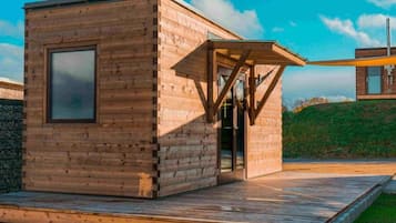 Uma cabana de madeira com porta de vidro e um pequeno alpendre.