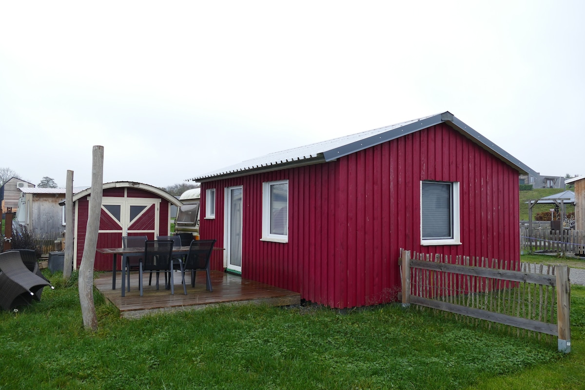 A red building with a porch and a table with chairs.
