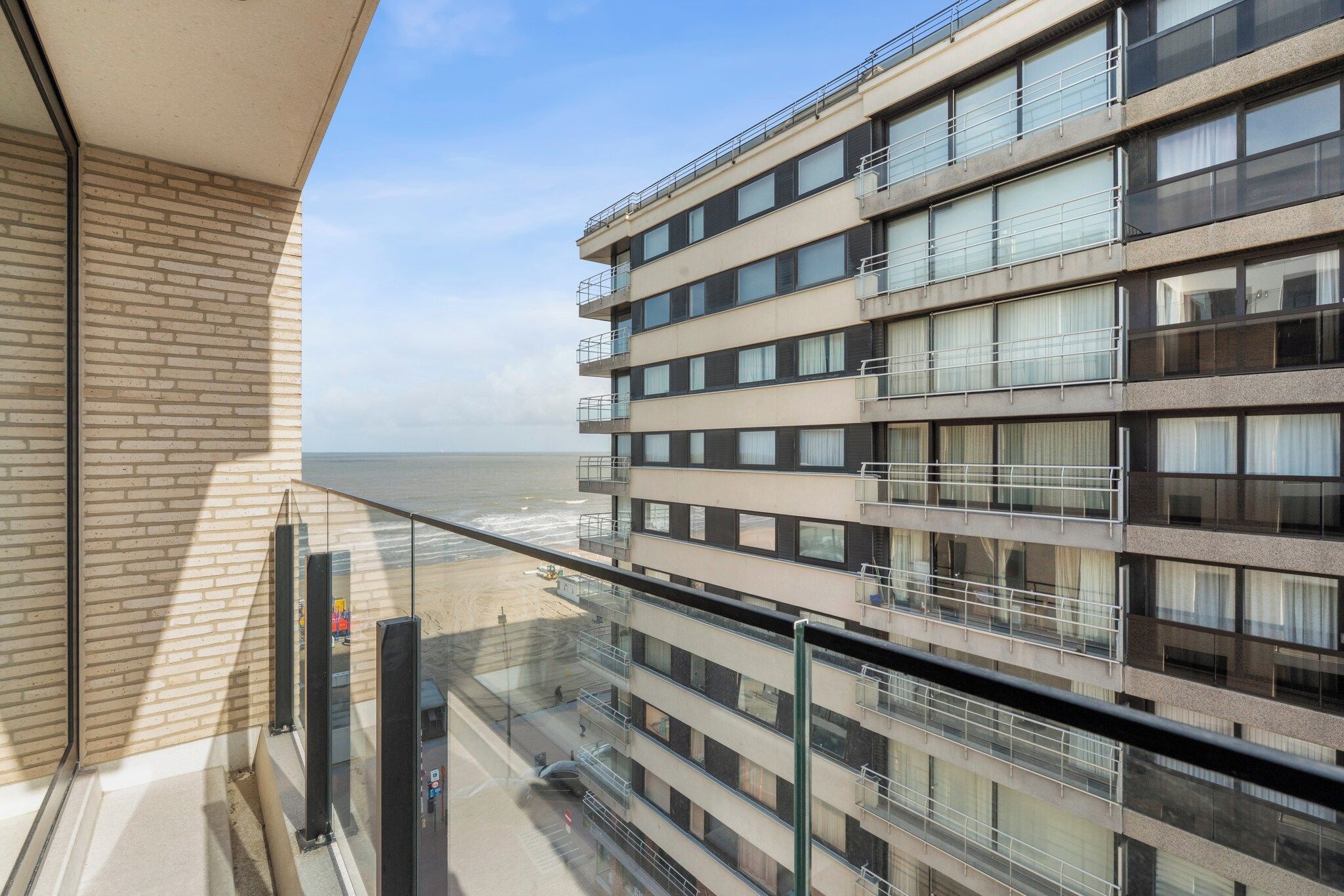 A multi-story building with balconies overlooking a beach.