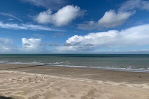 Uma praia com céu claro e mar calmo.