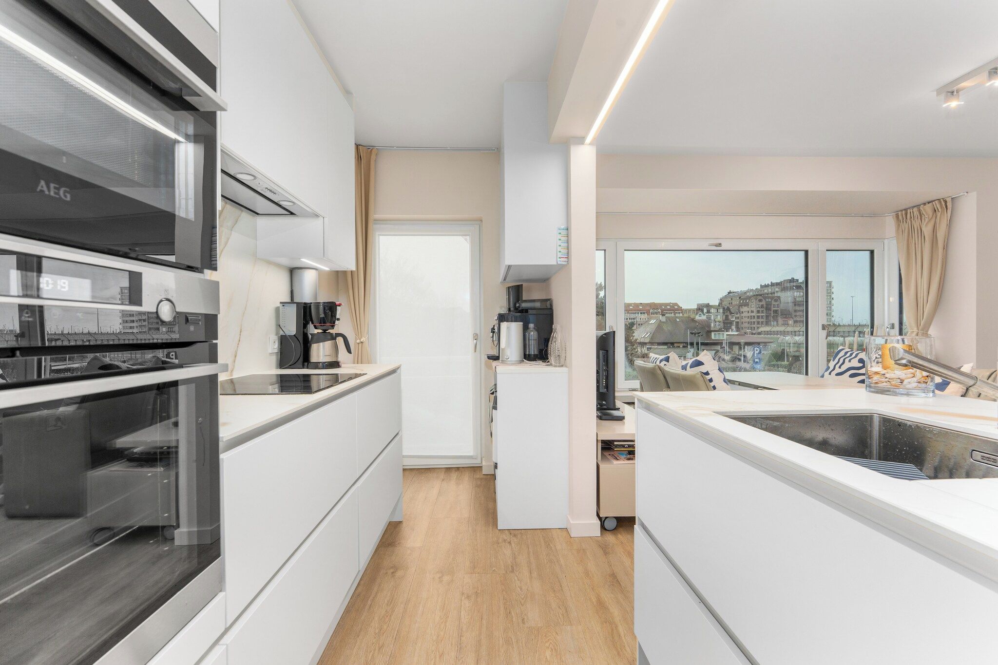 Cocina moderna con horno integrado, cafetera y vistas a la ciudad a través de amplios ventanales.