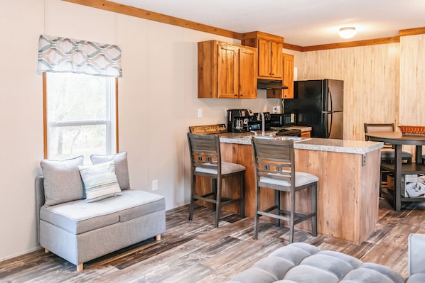 A compact kitchen with wooden cabinets, a black refrigerator, and a coffee maker. - Bronson - Wildlife Escape (Bronson)
