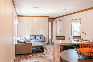 Un espacio habitable compacto con kitchenette, un sofá y una zona de comedor.
